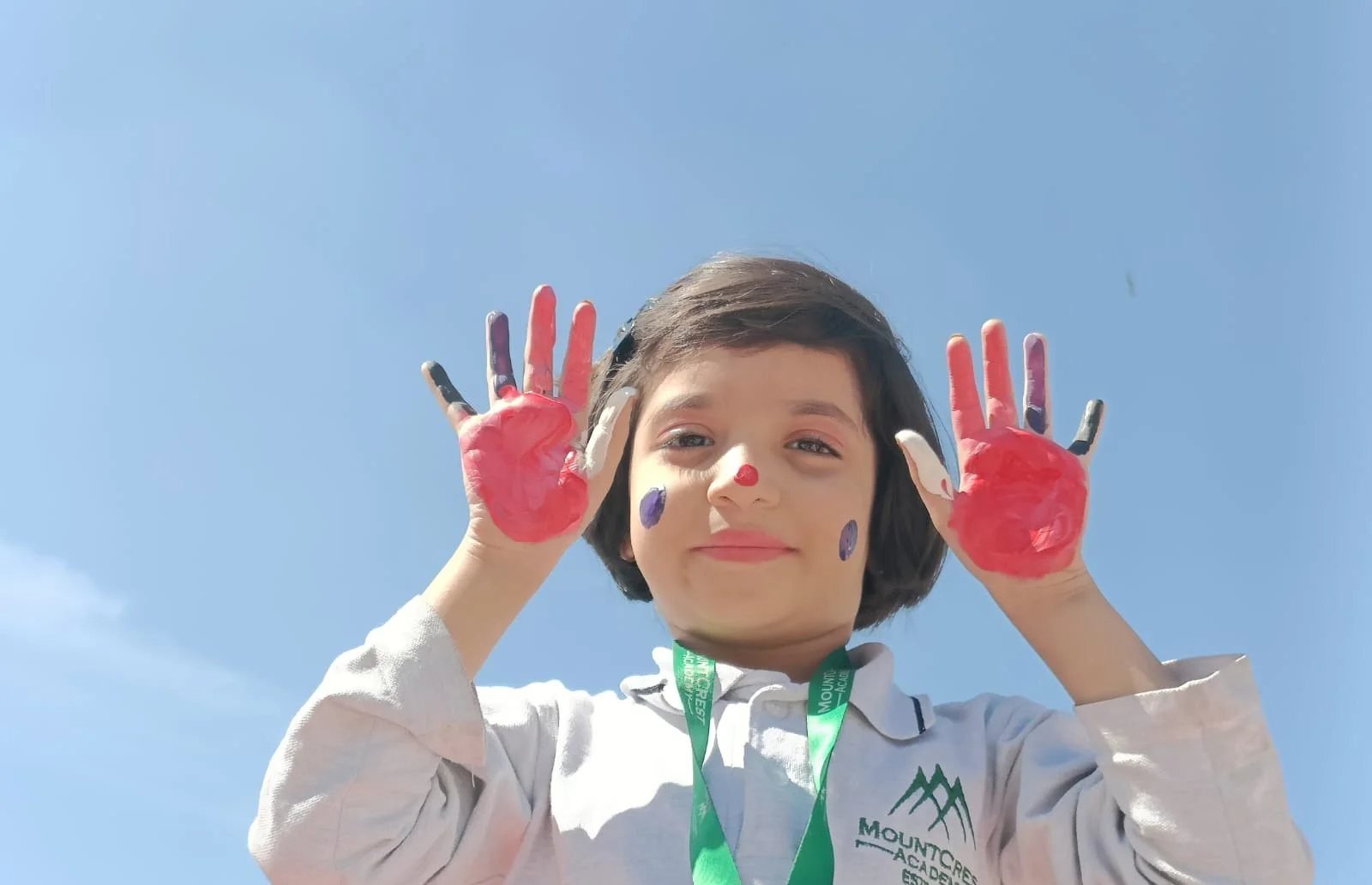 A primary student with painted hands on art day