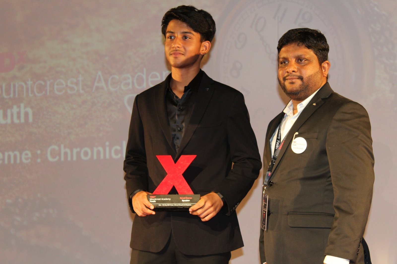A student speaker receives his TEDx speaker memento from the organiser